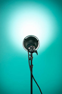 Image shows a standing spotlight shining a bright white light on a teal wall