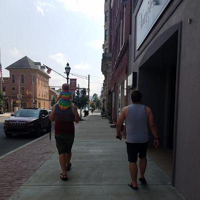 Man with toddler on shoulders walking down main street with his friend