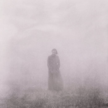 Man in long coat surrounded by white fog