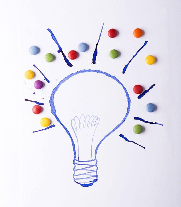 Drawing of a light bulb with dark blue lines and round, colored candy around it.