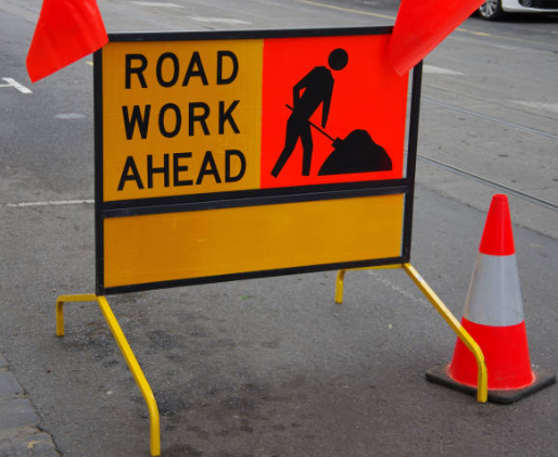 "Road Work Ahead" sign beside an orange and white cone
