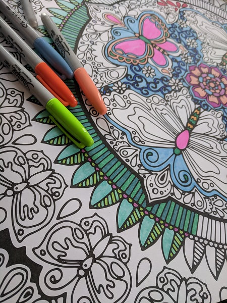 Partly coloured mandala with some Sharpie markers laying on top