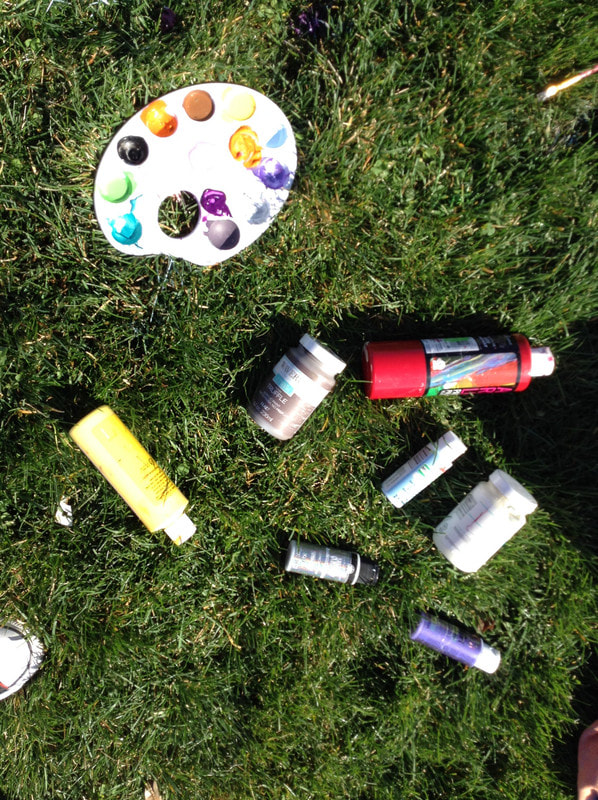 Bottles of paint and a palette on grass