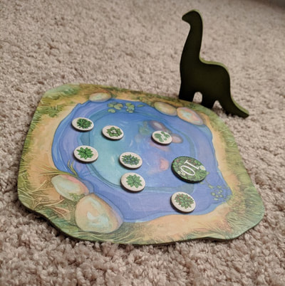 The watering hole from the board game Evolution with food pieces and the dinosaur player marker