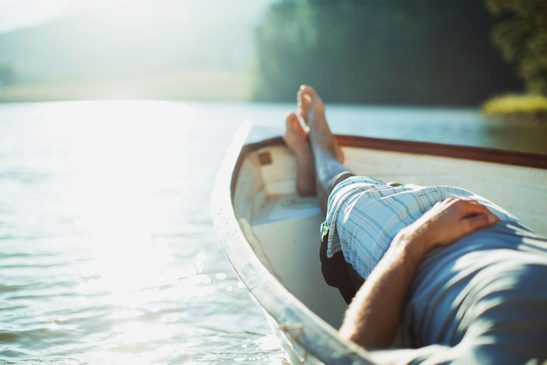 Barefoot man relaxing in rowboat